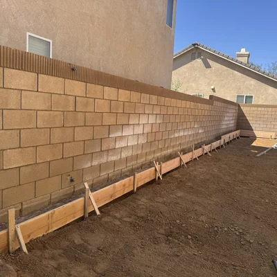 Timber footing forms set along a block retaining wall